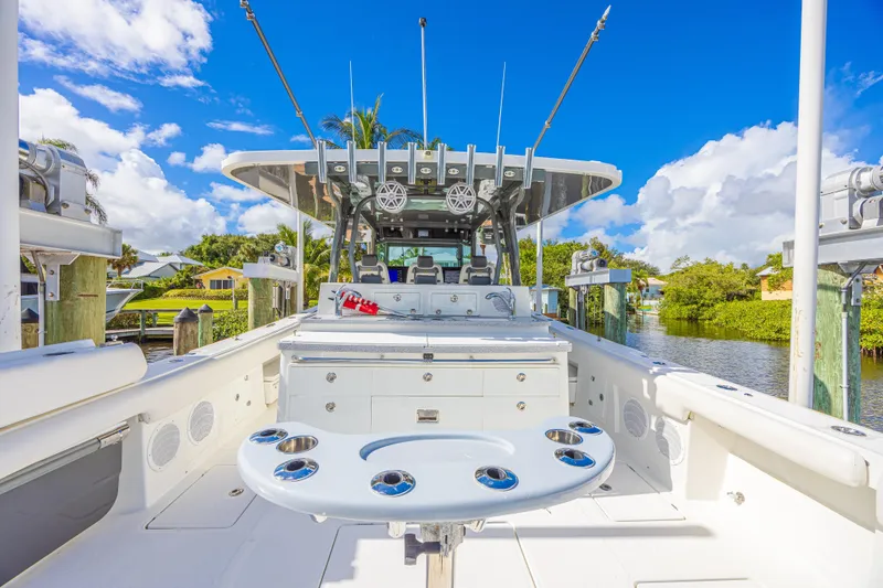 Slide: The Image of 2019 HCB 53 Sueños boat interior with fishing rod holders, docked by lush greenery. - 12