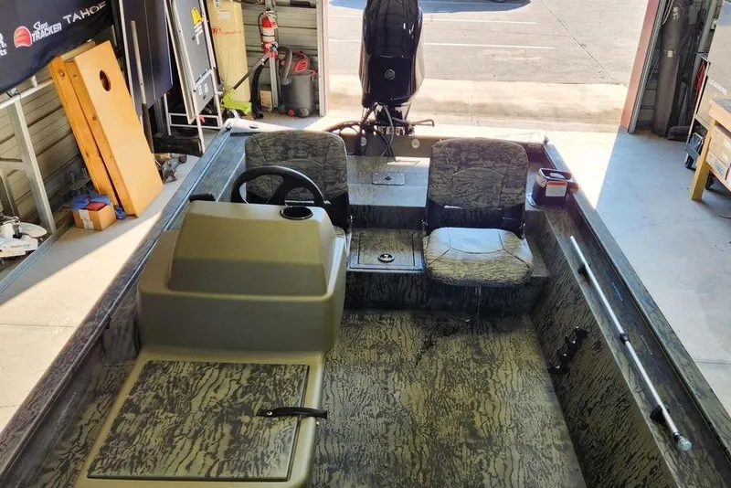 Slide: The Image of 2026 Tracker Grizzly 1754 SC boat interior with camouflage seats in a garage setting. - 10