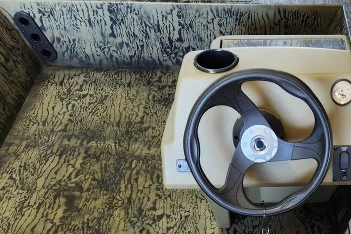 Slide: The Image of 2026 Tracker Grizzly 1754 SC boat interior with camo design and steering wheel. - 8