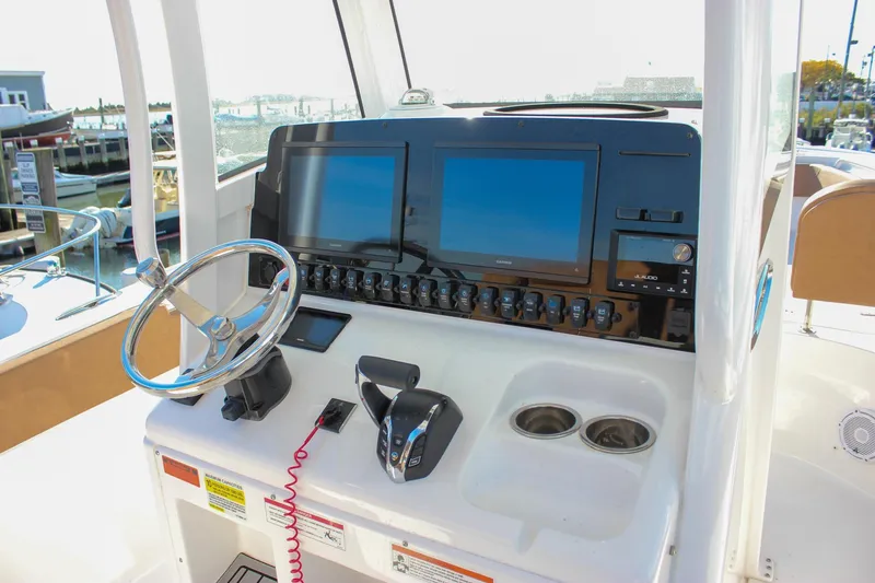 Slide: The Image of 2024 Sea Hunt Ultra 255 SE boat dashboard with dual screens and steering wheel. - 19