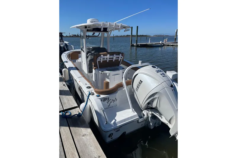 Slide: The Image of 2024 Sea Hunt Ultra 255 SE boat interior with Garmin navigation, docked at marina. - 2