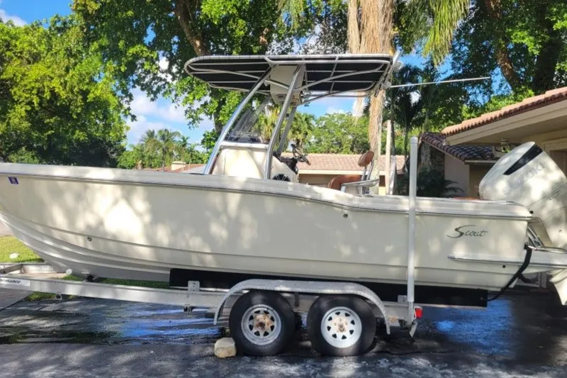 The Image of 2003 Scout 242 Sportfish boat on trailer, parked outdoors near palm trees. - 0