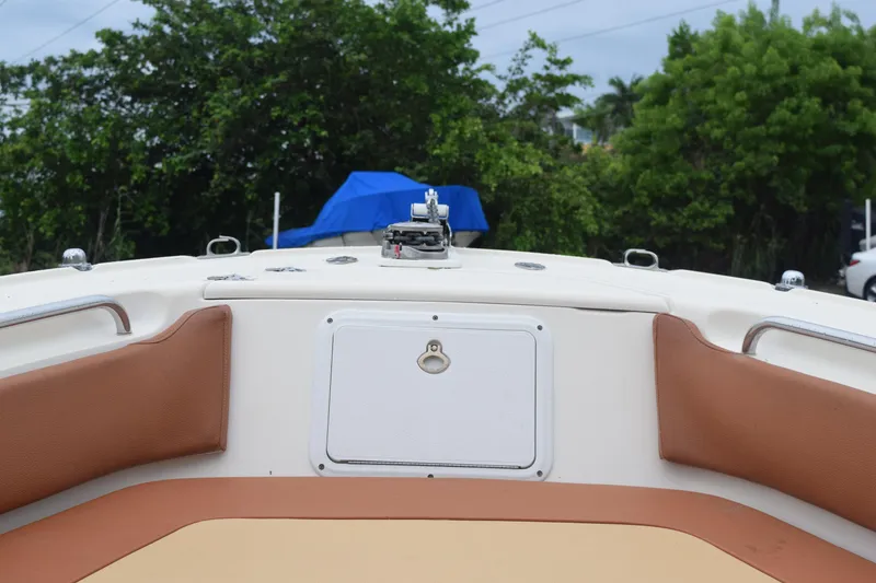 Slide: The Image of 2003 Scout 242 Sportfish boat interior with tan seating and lush greenery background. - 11