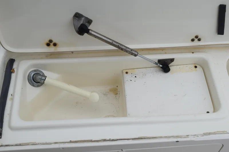 Slide: The Image of 2003 Scout 242 Sportfish boat on trailer, under metal structure, surrounded by greenery. - 164