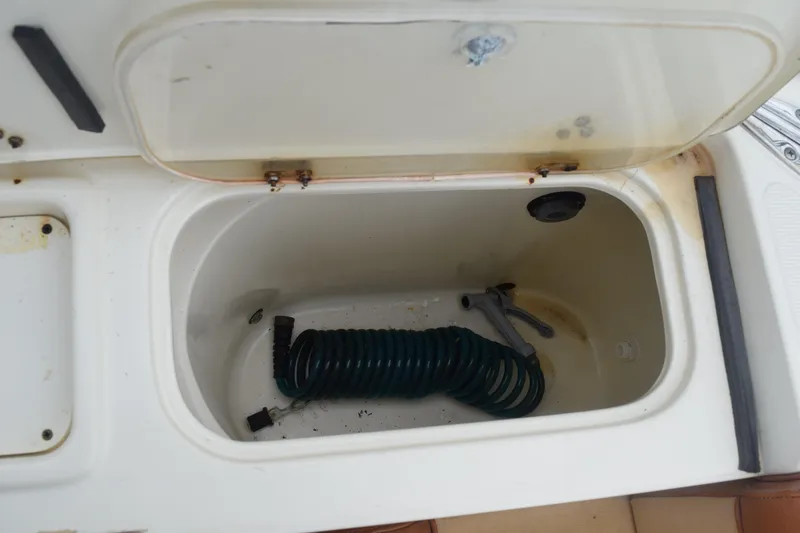 Slide: The Image of 2003 Scout 242 Sportfish boat on trailer, surrounded by greenery and other boats. - 168