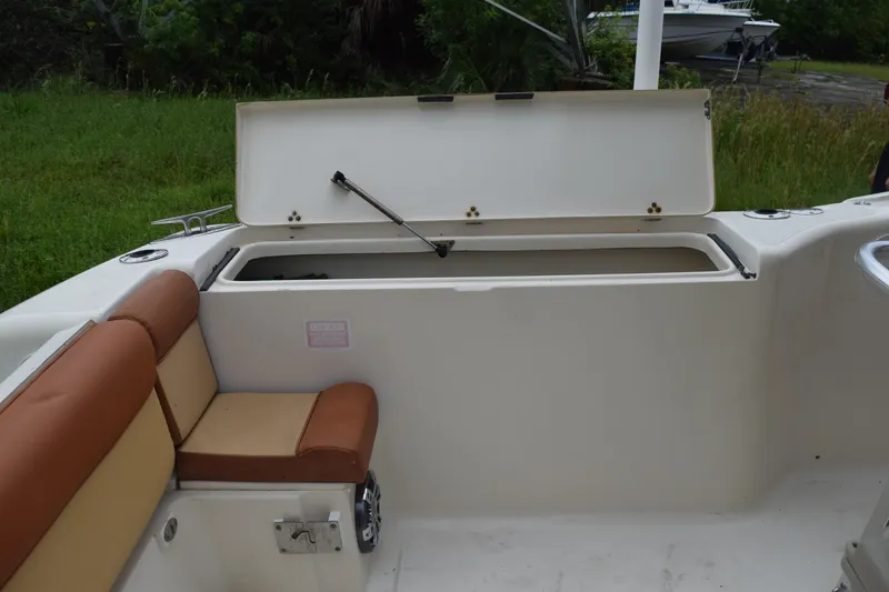 Slide: The Image of 2003 Scout 242 Sportfish boat interior with seating and console, surrounded by greenery. - 170