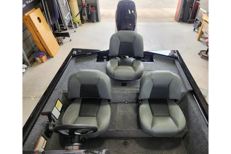 Slide: The Image of 2026 Tracker Pro 170 boat interior with three gray seats in a garage setting. - 9