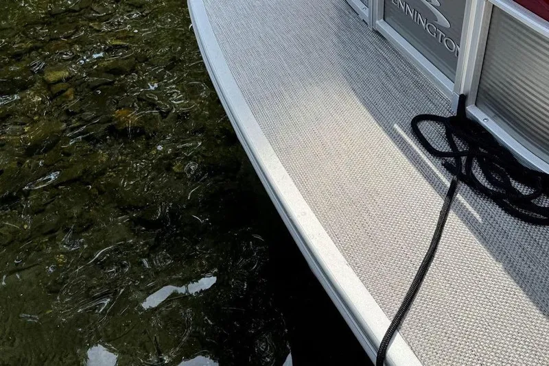 Slide: The Image of 2024 Bennington 22 SSRX pontoon boat interior with steering wheel, seating, and lake view. - 16