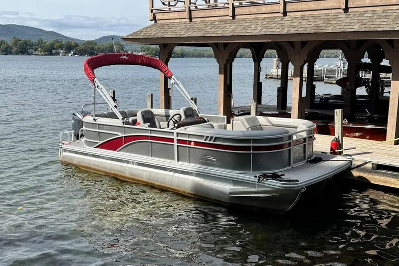 Slide: The Image of 2024 Bennington 22 SSRX pontoon boat docked on a serene lake. - 3