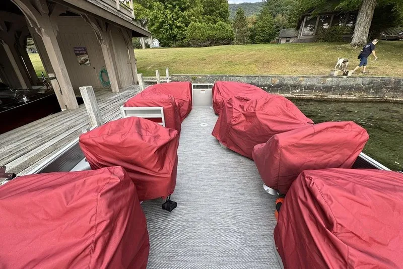 Slide: The Image of 2024 Bennington 22 SSRX pontoon boat with spacious seating, docked by a scenic lake. - 4