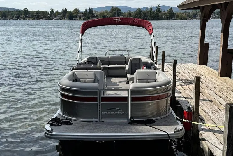 Slide: The Image of 2024 Bennington 22 SSRX pontoon boat with red canopy docked by a wooden pier. - 5