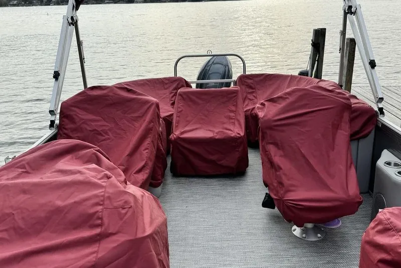 Slide: The Image of 2024 Bennington 22 SSRX boat interior with seating and cup holders by a dock. - 9