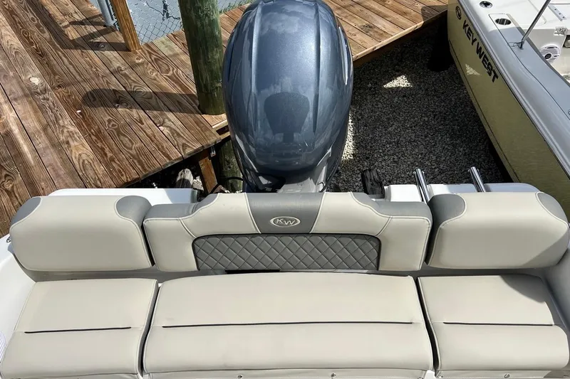 Slide: The Image of 2026 Key West 189 FS boat with cushioned seating and outboard motor at dock. - 10