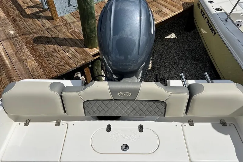 Slide: The Image of 2026 Key West 189 FS boat with cushioned seating and outboard motor, docked on wooden pier. - 11