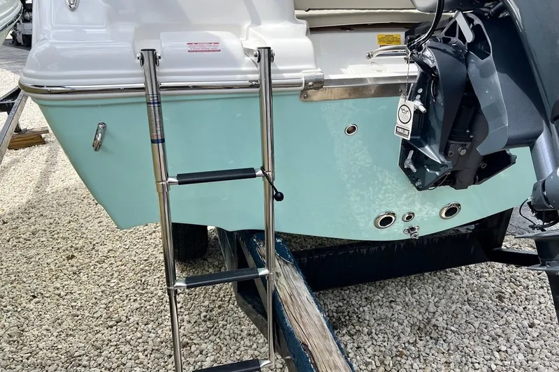 Slide: The Image of 2026 Key West 189 FS boat stern with ladder and motor mount on gravel. - 7