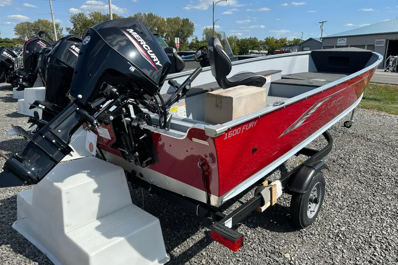 Slide: The Image of 2025 Lund 1600 Fury Tiller boat with Mercury engine, red exterior, on a trailer. - 2