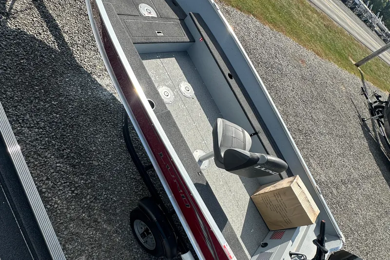 Slide: The Image of 2025 Lund 1600 Fury Tiller boat on gravel, featuring a seat and storage compartments. - 6
