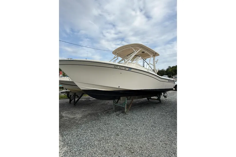 Slide: The Image of 2020 Grady-White Freedom 255 boat on gravel, under a cloudy sky. - 1