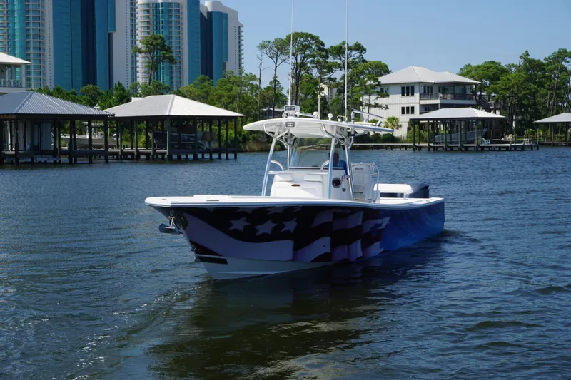 Slide: The Image of 2012 Regulator 32 Forward Seating boat on water, with American flag design, near waterfront buildings. - 51