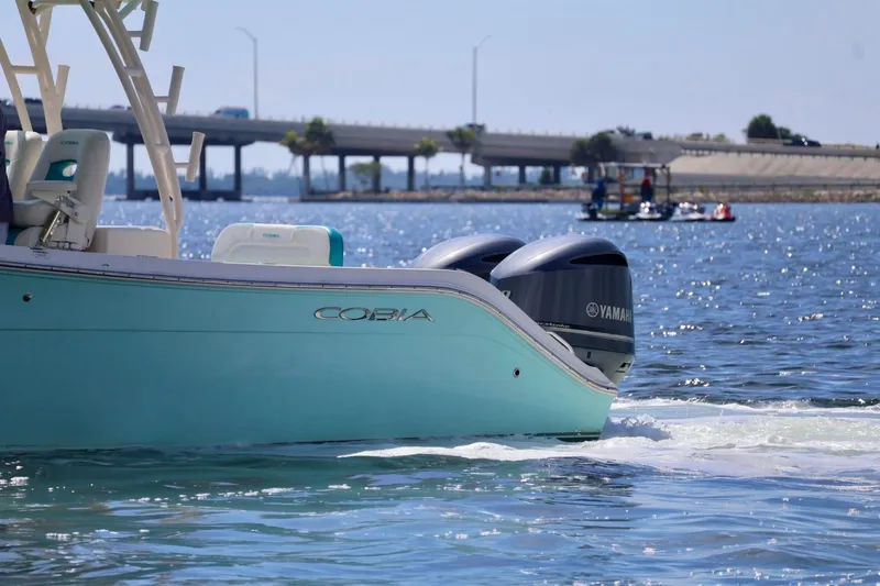 Slide: The Image of 2015 Cobia 29’6 boat with Yamaha engines on a sunny day near a bridge. - 2