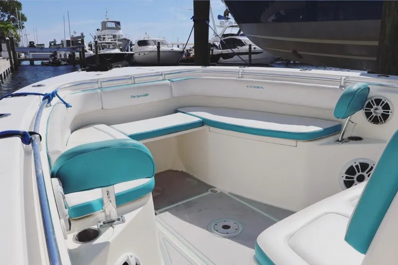 Slide: The Image of 2015 Cobia 29’6 boat interior with teal and white seating at marina. - 7
