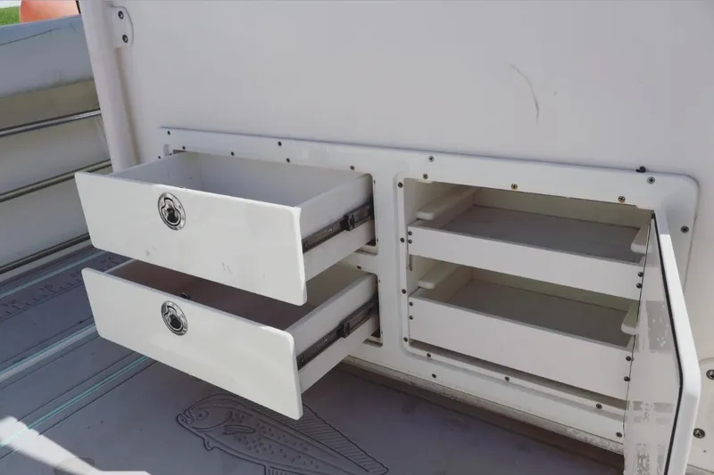 Slide: The Image of 2015 Cobia 29’6 boat storage compartments with open drawers and shelves. - 9
