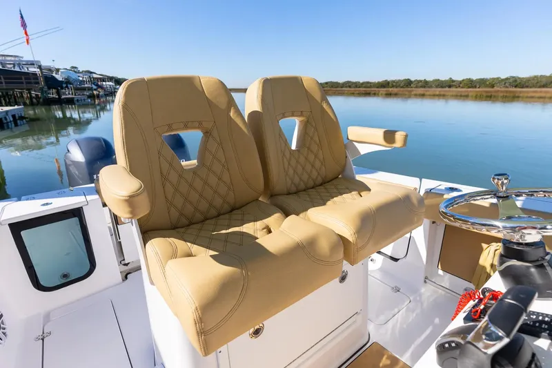 Slide: The Image of Manufacturer Provided Image: 2025 Sportsman Open 262 Center Console boat with tan seats, steering wheel, and calm water backdrop. - 7