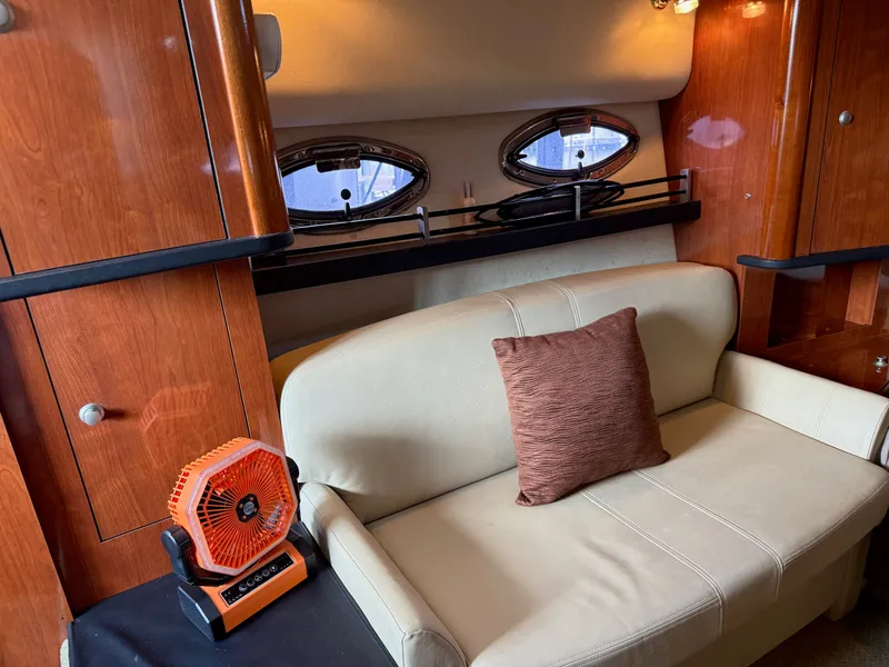Slide: The Image of Interior of 2007 Sea Ray 290 Sundancer with beige sofa, pillow, and small fan. - 13