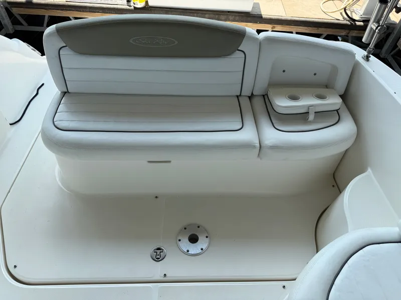 Slide: The Image of 2007 Sea Ray 290 Sundancer boat seating area with white cushioned bench and cup holders. - 24