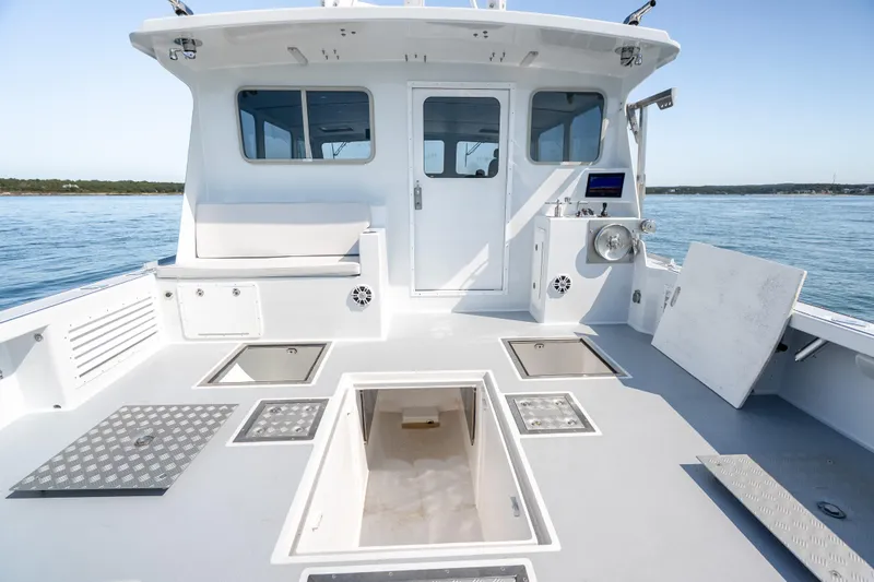 Slide: The Image of 2025 Mussel Ridge 42 boat deck with storage hatches, white cabin, and ocean view. - 27