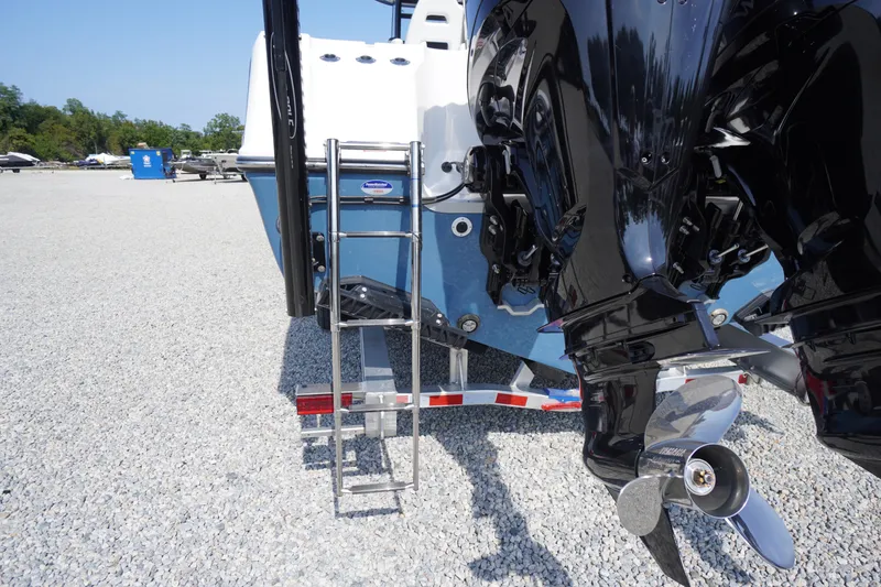 Slide: The Image of 2026 Tidewater 302 CC Adventure boat with dual outboard motors and ladder on gravel lot. - 82