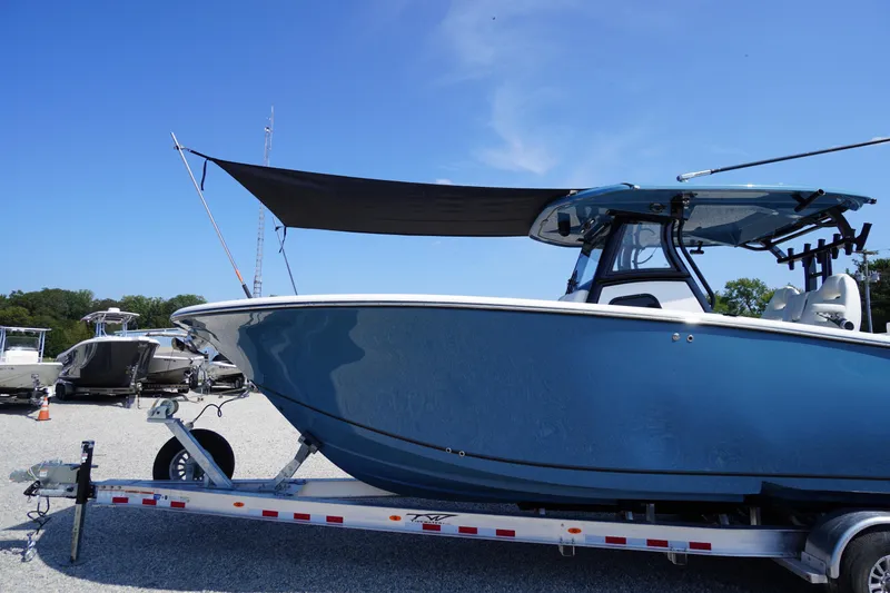 Slide: The Image of 2026 Tidewater 302 CC Adventure boat on trailer, blue hull, sunny day. - 92