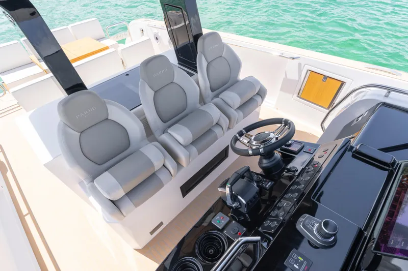 Slide: The Image of 2025 Pardo Yachts P38 helm with dual screens, steering wheel, and controls on open water. - 44