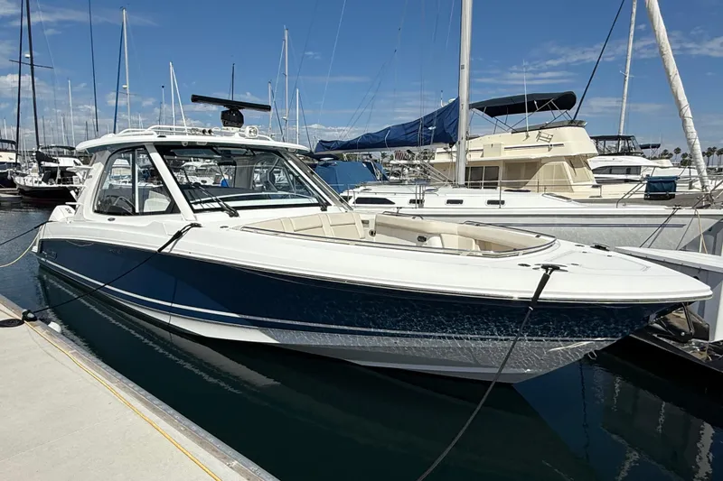 The Image of 2023 Boston Whaler 380 Realm docked at marina under clear blue sky. - 0