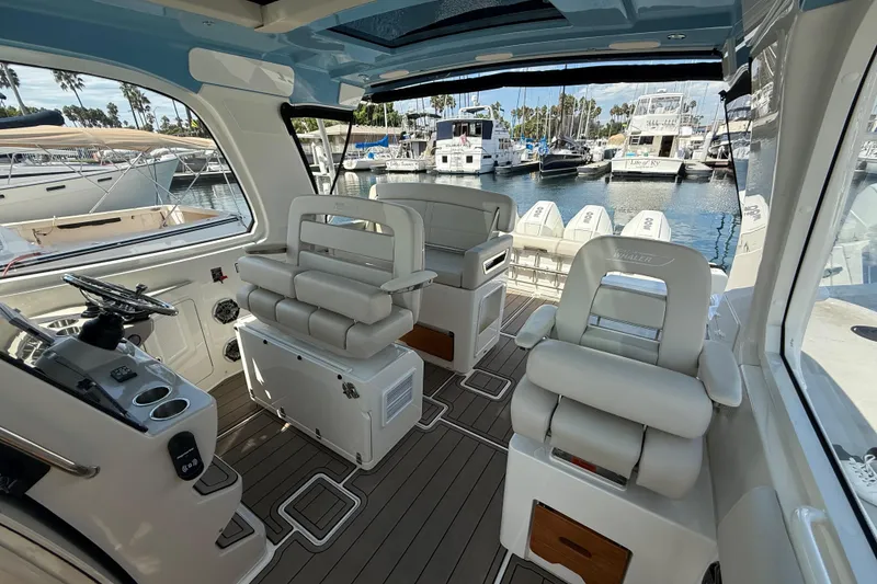 Slide: The Image of 2023 Boston Whaler 380 Realm interior with helm, seating, and marina view. - 15