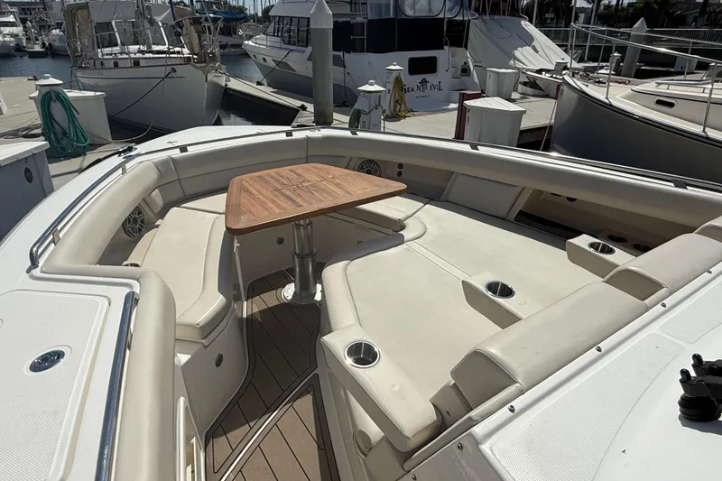 Slide: The Image of 2023 Boston Whaler 380 Realm boat interior with seating and table at marina. - 19