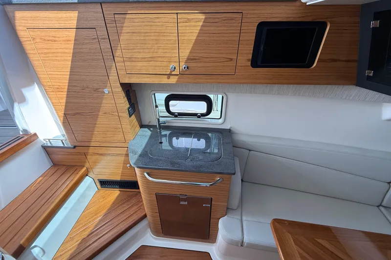 Slide: The Image of 2023 Boston Whaler 380 Realm interior with wood cabinetry and compact kitchen area. - 25