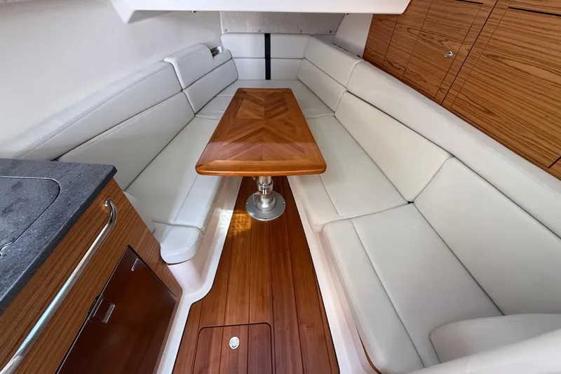 Slide: The Image of 2023 Boston Whaler 380 Realm interior with white seating and wooden table. - 26