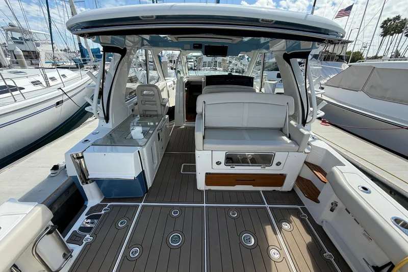 Slide: The Image of 2023 Boston Whaler 380 Realm boat interior with seating and deck, docked at marina. - 9