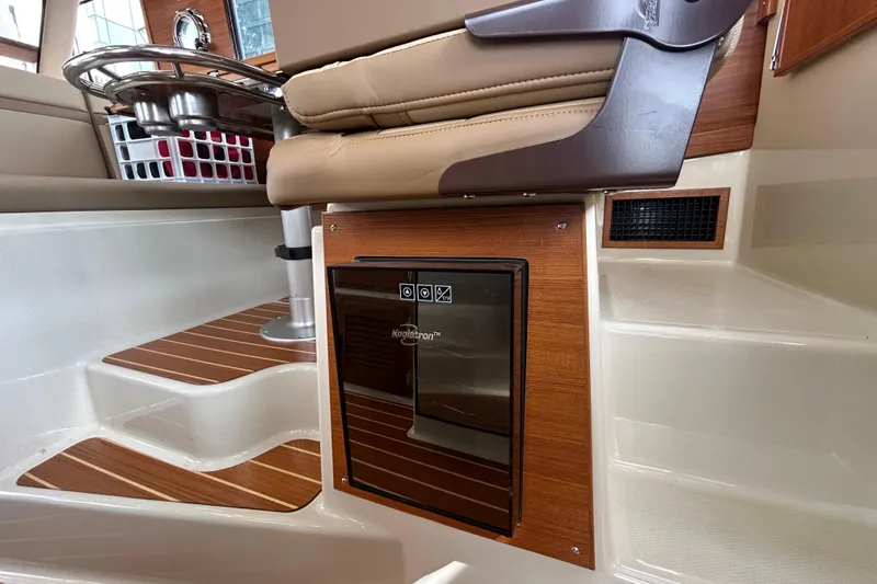 Slide: The Image of Interior of 2023 Ranger Tugs R-31 CB, featuring a compact fridge and wooden accents. - 10