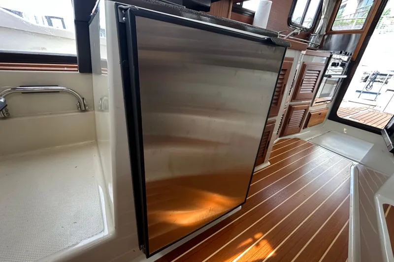 Slide: The Image of 2023 Ranger Tugs R-31 CB interior with stainless steel fridge and wooden flooring. - 11