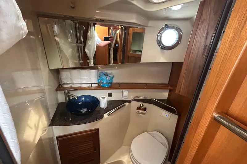 Slide: The Image of 2023 Ranger Tugs R-31 CB bathroom with modern sink, toilet, and porthole window. - 14