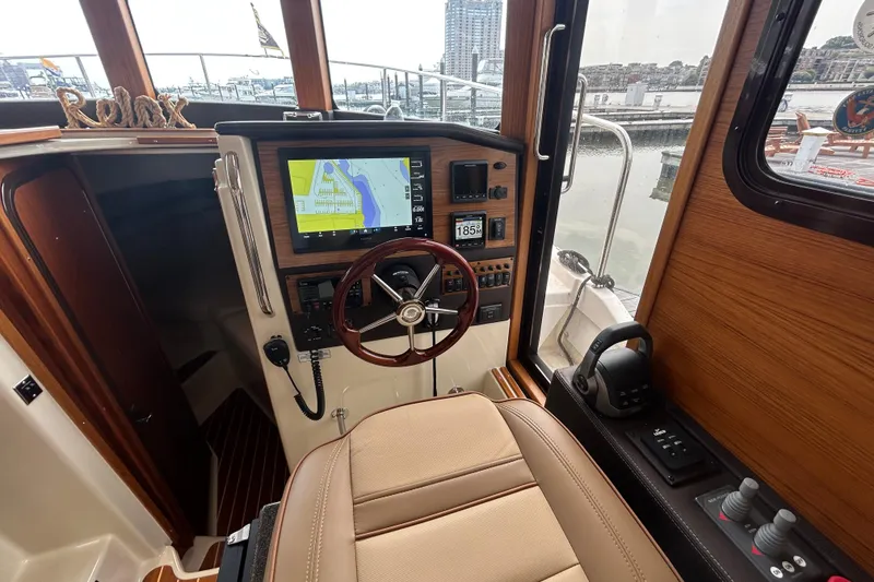 Slide: The Image of 2023 Ranger Tugs R-31 CB helm with navigation display and wooden steering wheel. - 16