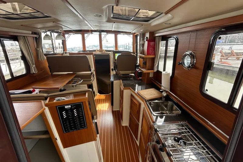 Slide: The Image of 2023 Ranger Tugs R-31 CB interior with wood finish, kitchen, and seating area. - 19