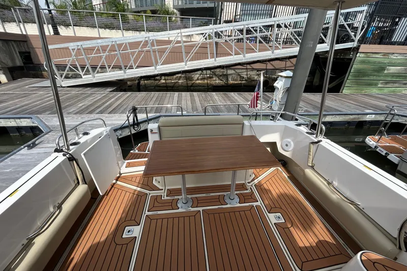 Slide: The Image of 2023 Ranger Tugs R-31 CB boat deck with wooden table and seating at a marina. - 20