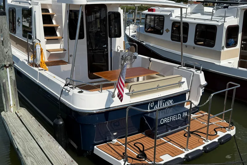 Slide: The Image of 2023 Ranger Tugs R-31 CB boat docked, featuring a spacious deck and American flag. - 3
