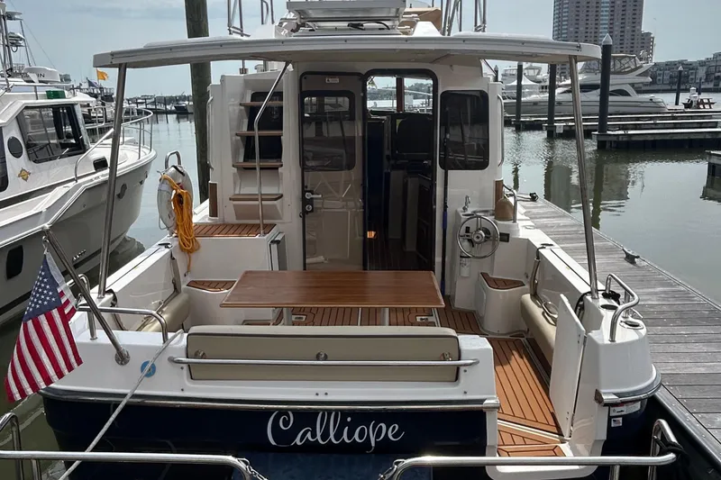 Slide: The Image of 2023 Ranger Tugs R-31 CB boat docked, featuring a spacious deck and American flag. - 5