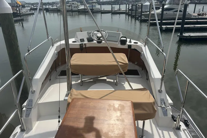 Slide: The Image of 2023 Ranger Tugs R-31 CB boat cockpit with covered seating, docked at a marina. - 6