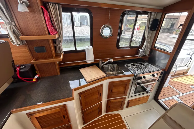 Slide: The Image of 2023 Ranger Tugs R-31 CB interior kitchen with wood cabinetry and stainless steel appliances. - 8