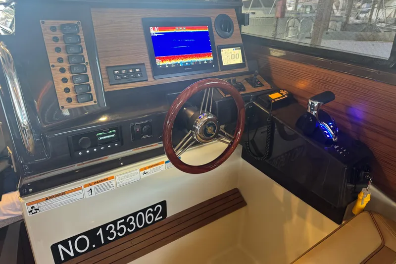 Slide: The Image of 2025 Ranger Tugs R-27 helm with advanced navigation system and wooden steering wheel. - 11